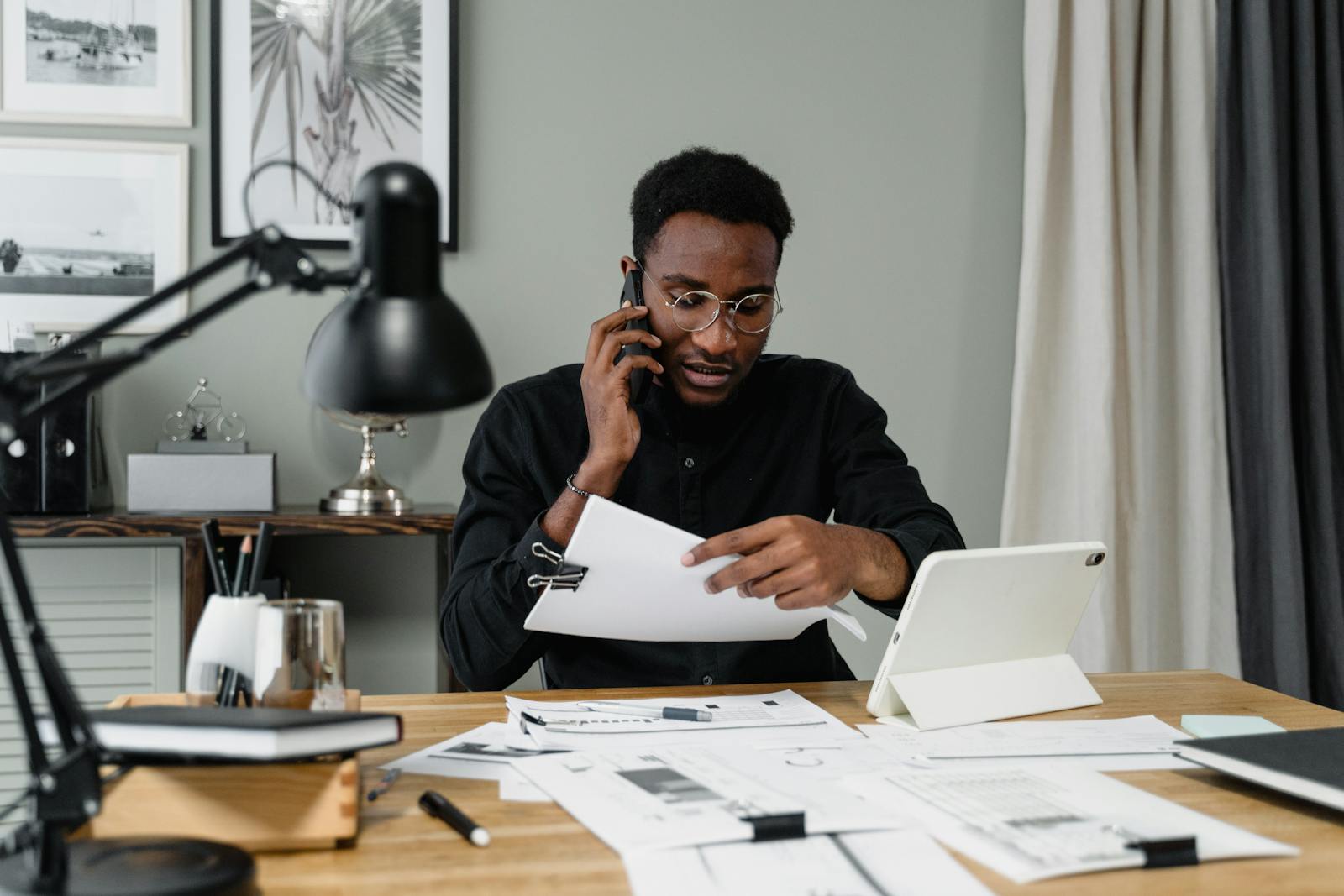 Focused businessman reviewing documents while speaking on phone in modern office. clerk